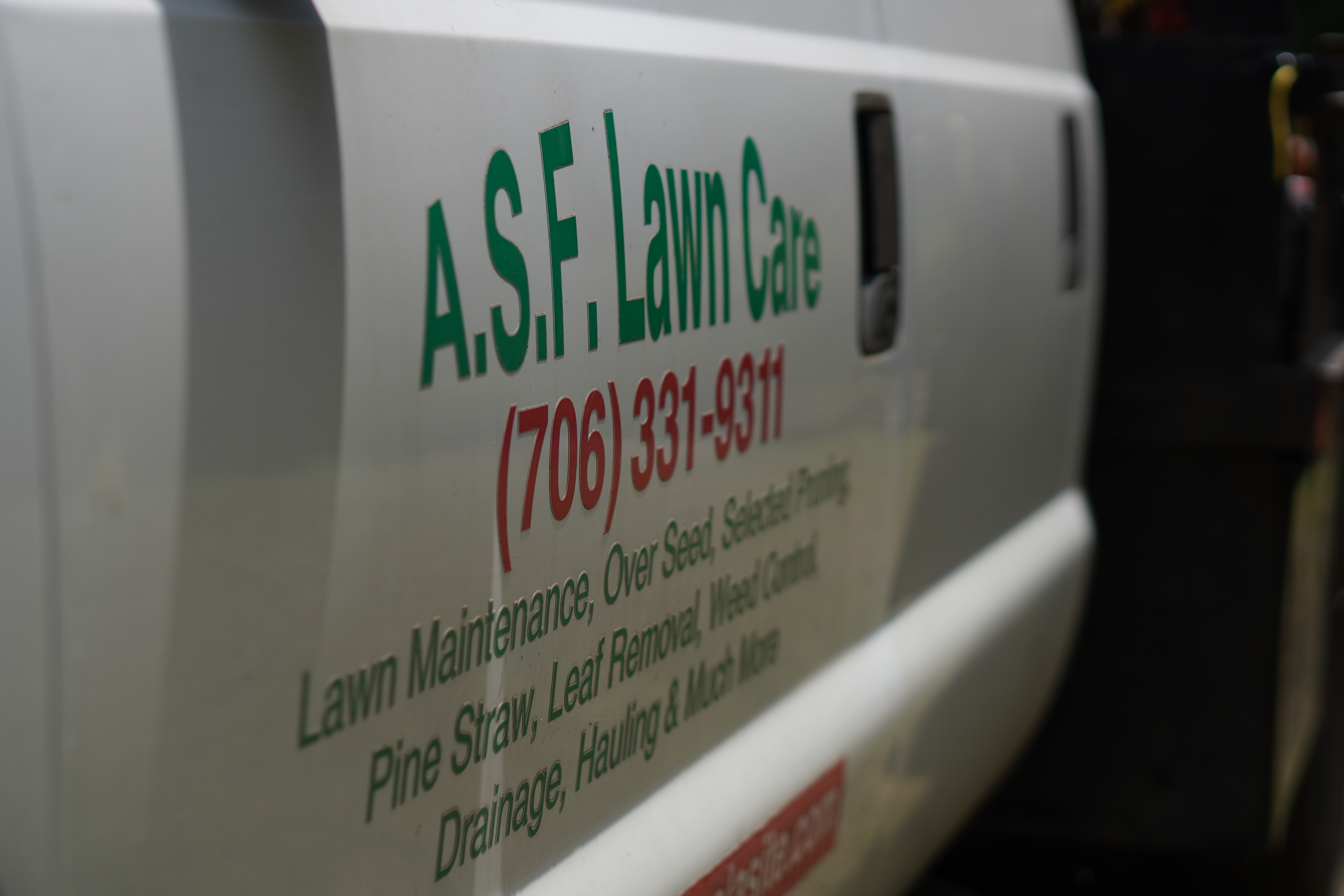 Close-up of the A.S.F. Lawn Care truck decal, showing the phone number (706) 331-9311 and list of services